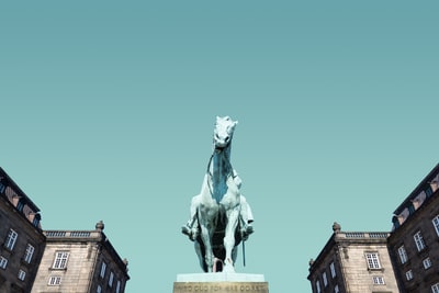 白马雕像附近房屋在蓝色的天空下
